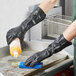 A person wearing black Showa neoprene gloves cleaning a surface.