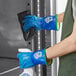 A person wearing Showa blue thermal insulated gloves cleaning a refrigerator.