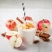 A glass of white liquid with Oregon Fruit In Hand Apple Harvest puree and cinnamon sticks.