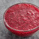 A glass bowl filled with diced red raspberries.