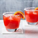 Two glasses of red margaritas with salted orange slices.