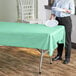 A person holding a plate with a mint green plastic table cover on a table.