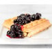 A white plate with a waffle topped with Oregon Fruit Blueberry Filling and blueberries.