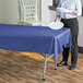 A woman standing at a table with a navy blue plastic tablecloth holding a white plate.