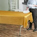 A woman holding a white plate over a table with a metallic gold plastic table cover.