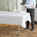 A woman holding plates on a table with a white plastic table cover.