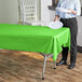 A woman standing in front of a table with a lime green plastic tablecloth on it.