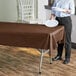 A woman holding a plate over a table with a chocolate plastic table cover.