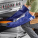 A person wearing blue Tucker Safety gloves puts a pie in the oven.