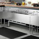 A Regency stainless steel underbar sink with drainboards and faucets.