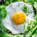 A plate with a Yo Egg Plant-Based sunny side up egg with vegetables and herbs.