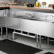 A Regency stainless steel underbar sink with (2) 12" drainboards and faucet on a counter.