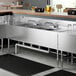 A Regency stainless steel underbar sink with two faucets and two drainboards.