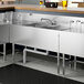 A Regency stainless steel underbar sink with (2) drainboards on a counter in a professional kitchen.