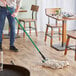 A person mopping the floor with a Lavex mop with a green handle.