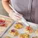 A woman using a Carlisle Sparta Spectrum pastry brush to glaze pastries.