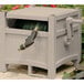 A Suncast taupe hose storage hideaway box with a hose inside.