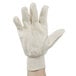 A person's hand holding a white Cordova Premium Ramie / Cotton Blend canvas glove.