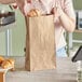 A woman putting food in a Duro brown paper bag.