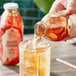 A hand pouring Harney & Sons Blood Orange Iced Tea into a glass with ice.