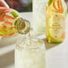A person pouring Harney & Sons Organic White Peach Matcha Iced Tea into a glass.