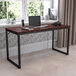 A Flash Furniture Tiverton mahogany and black office desk with a laptop and other objects on it.