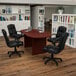 A mahogany oval conference table with black leather chairs around it.