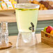A clear acrylic beverage dispenser with a spigot, filled with a light-colored drink and lemon slices, sitting on a countertop.