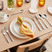 A table set with Acopa Lore stainless steel knives and forks on a table.