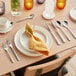 A silver fork on a table set with plates and cutlery.