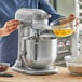 A woman using a KitchenAid countertop mixer to mix food.