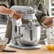 A woman using a KitchenAid bowl lift countertop mixer to mix flour and chocolate chips.