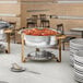 A buffet table with silver and gold Choice Deluxe chafers on a white surface.