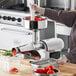 A woman using a Tre Spade electric tomato mill to process tomatoes on a counter.