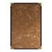 A brown brushed metallic menu cover with a gold frame on a brown surface.