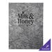 A H. Risch, Inc. brushed metallic steel menu cover with black and silver custom inserts on a table in a brunch café.