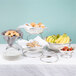 A table with a variety of food on display using American Metalcraft stainless steel risers.