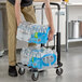 A man using a Lavex aluminum platform truck to carry water bottles.