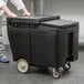 A man standing next to a Cambro black plastic mobile ice bin.