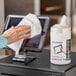 A hand using a PDI Healthcare Easy Screen Cleaning Wipe to clean a screen.