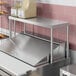 A stainless steel counter with an Avantco stainless steel single deck overshelf on it.
