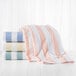 A stack of 1888 Mills Fibertone Cabana pool towels with peach stripes on a white surface.