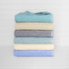 A stack of folded sandstone pool towels with a blue border.