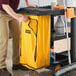 A man using a Lavex Premium yellow bag on a cleaning cart.