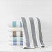 A stack of 1888 Mills tan stripe pool towels on a white shelf.