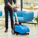 A man using a Lavex walk behind floor scrubber to clean a floor in a professional kitchen.