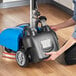 A person using a Lavex walk behind floor scrubber to clean a floor.