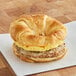 A Grand Prairie Sausage, Egg, and Cheese Croissant breakfast sandwich on a white napkin.