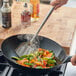 A person cooking food in a wok with an Emperor's Select small wok spatula.