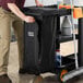 A man putting a black Lavex Premium vinyl bag with a zipper on a cleaning cart.